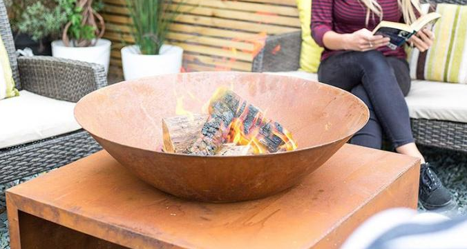 屋外の庭の丸太の貯蔵を用いる現代錆ついたCortenの鋼鉄火ボール
